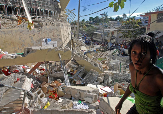 Une jeune femme erre, hagarde, au milieu des ruines à Port-au-Prince, le 13 janvier 2010. La veille, un séisme d'une magnitude de 7,3 sur l'échelle de Richter a ravagé la capitale d'Haïti, faisant plus de 200 000 morts et autant de blessés. 